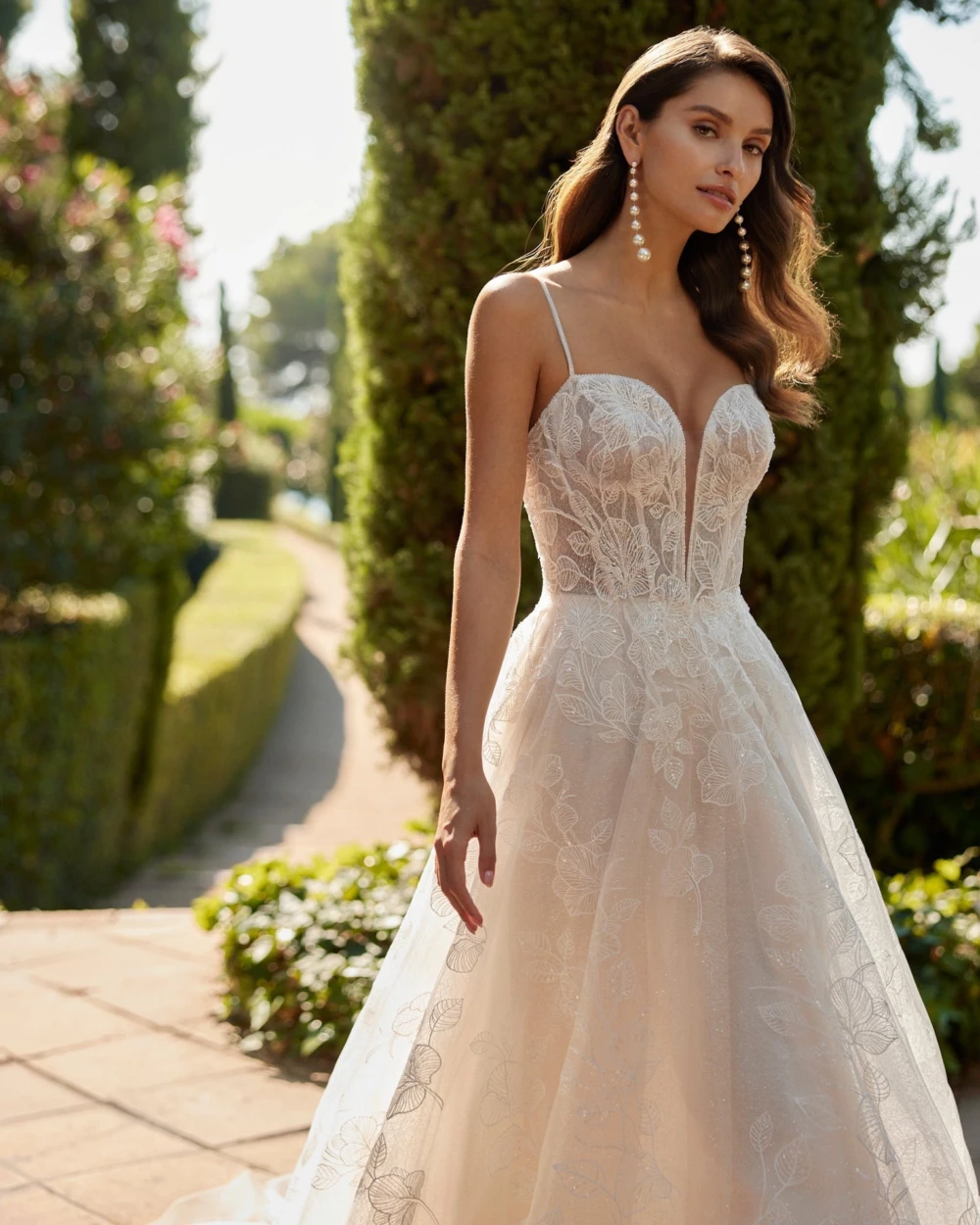 Model wearing blush a-line wedding dress made with lace detail and sequins.